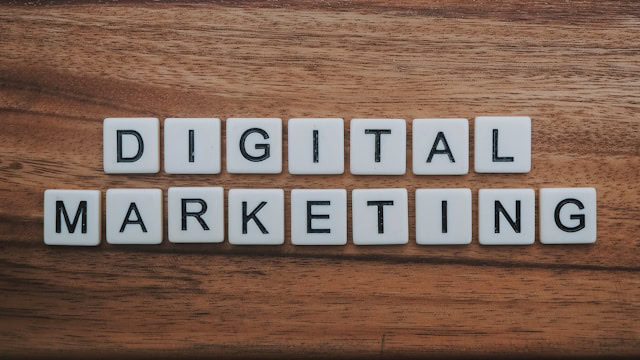 Auf einer Holzoberfläche angeordnete weiße Buchstabensteine ergeben in zwei Reihen das Wort „DIGITAL MARKETING“ und deuten damit die Frage an: Kann man SEO für seinen Online-Erfolg selber machen?.