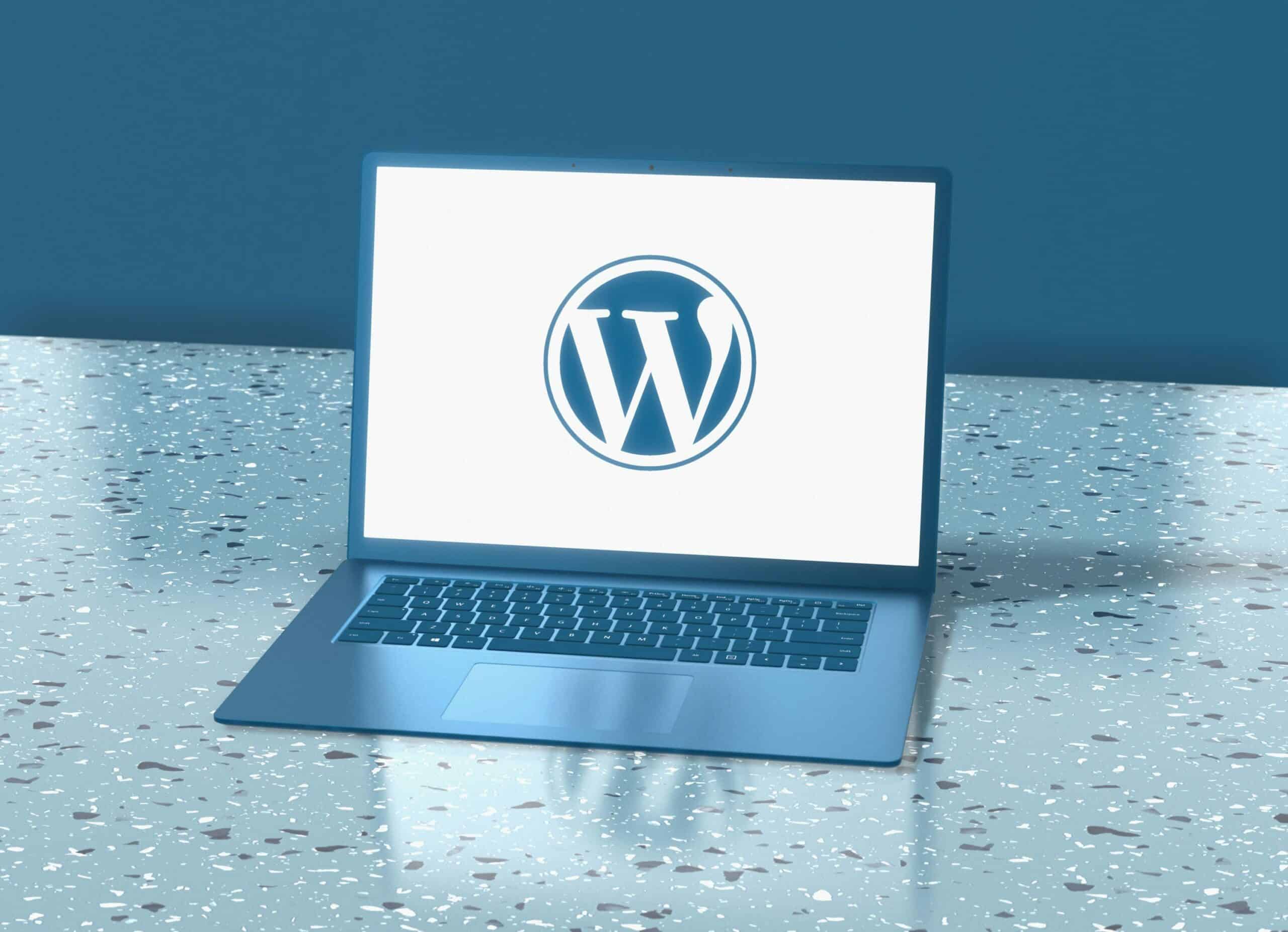 Ein Laptop auf einer gesprenkelten Oberfläche zeigt auf seinem Bildschirm das WordPress-Logo vor blauem Hintergrund und lädt die Benutzer ein, es zu erkunden und zu fragen: Ist WordPress sicher?.