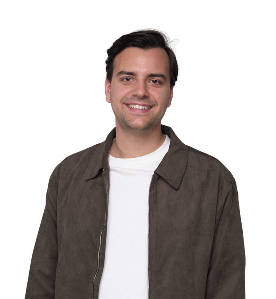 Ein Mann mit kurzen dunklen Haaren, der eine braune Jacke über einem weißen T-Shirt trägt, steht und lächelt vor einem schlichten Hintergrund.