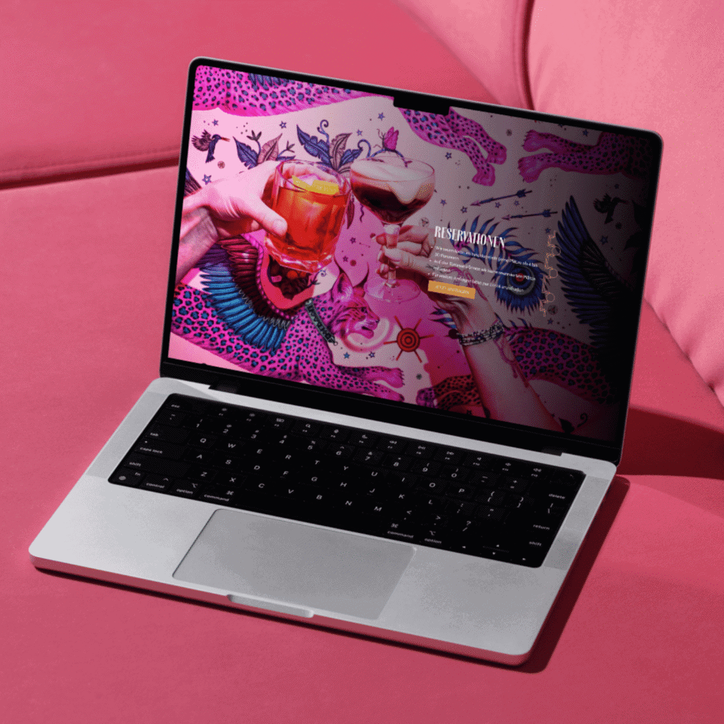 Ein Webdesign der Amber Bar in Basel auf einem Laptop auf einer rosafarbenen Couch.