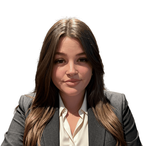 Eine Frau mit langen braunen Haaren, die eine weiße Bluse und einen dunklen Blazer trägt, sitzt vor einem schlichten weißen Hintergrund und schaut mit neutralem Blick in die Kamera.