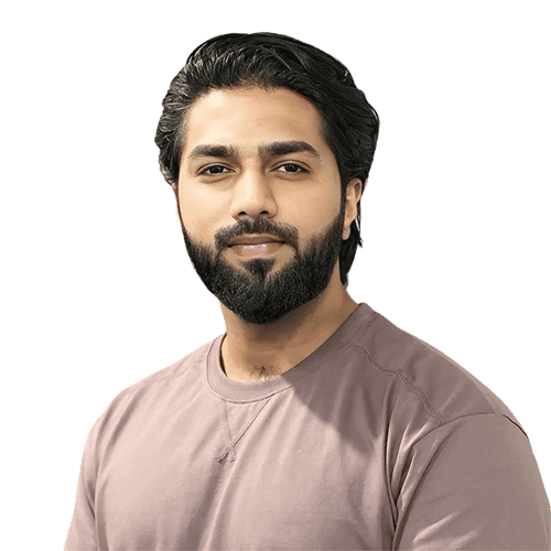 Ein Mann mit dunklem Haar und Bart, der ein lilafarbenes T-Shirt trägt, blickt vor einem schlichten hellen Hintergrund in die Kamera.